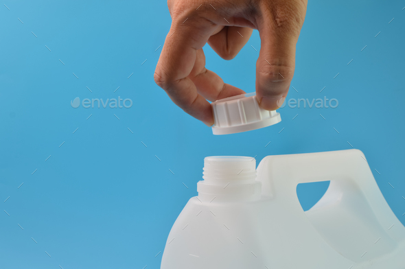 Hand opened white gallon bottle cap isolated on a blue background