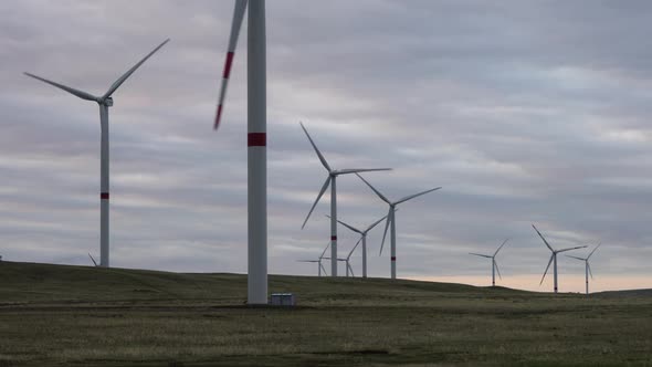 Motion the Blades of a Large Wind Turbine in a Field Against a Background of Orange Sunset on the alt
