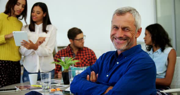 Portrait of smiling executive sitting with arms crossed alt
