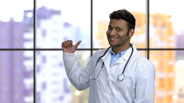 Young Darkskinned Hindu Doctor Spinning and Pointing Back with His Thumb alt