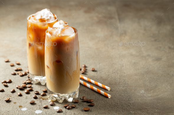 Ice coffee in a glass with cream poured over and coffee beans