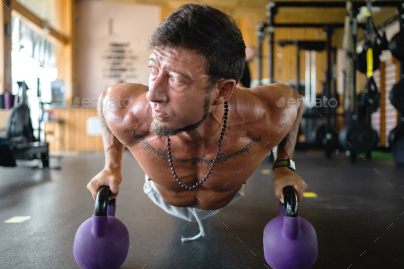 Man using kettlebells to do push-ups in a gym