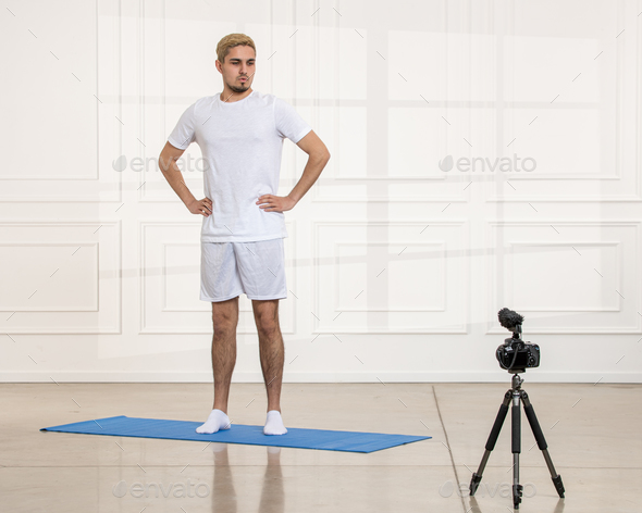 sport blogger fit young strong handsome guy recording work outs from home video standing still