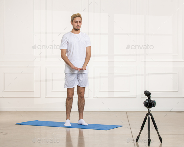 sport blogger young fit strong handsome guy recording work outs from home video standing still