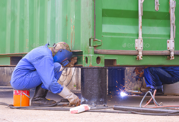 Two welders are welding metal foundation to renovate and improvement outdoor office container