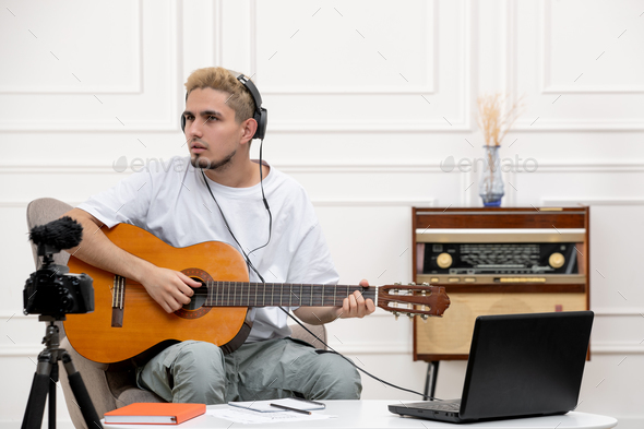 elearning cute young handsome guy remotely giving guitar classes at home with radio