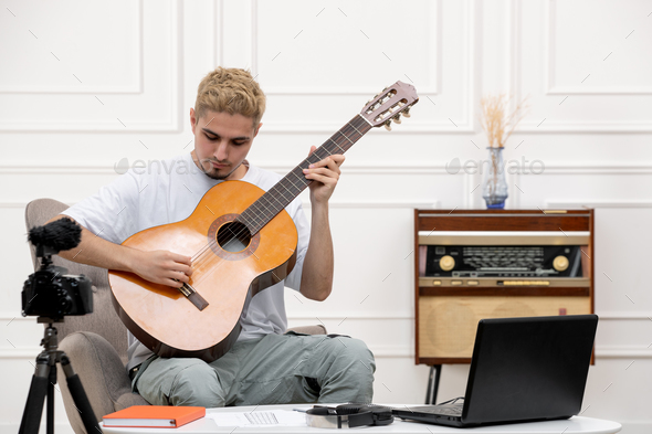 elearning handsome cute young guy remotely giving guitar classes at home holding guitar