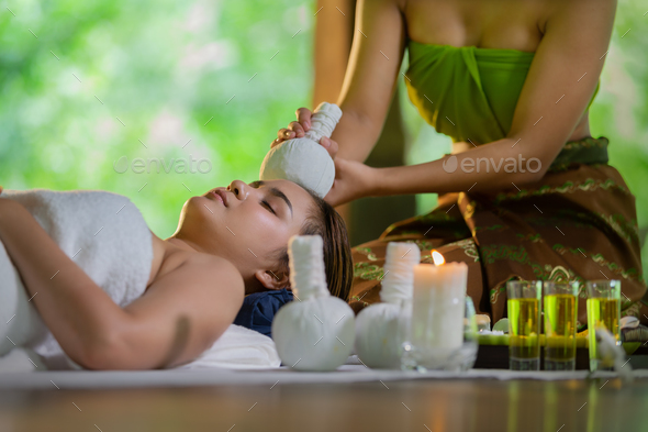 Young Asia beautiful woman during massage with spa herbal compress with oil and herbal set near site