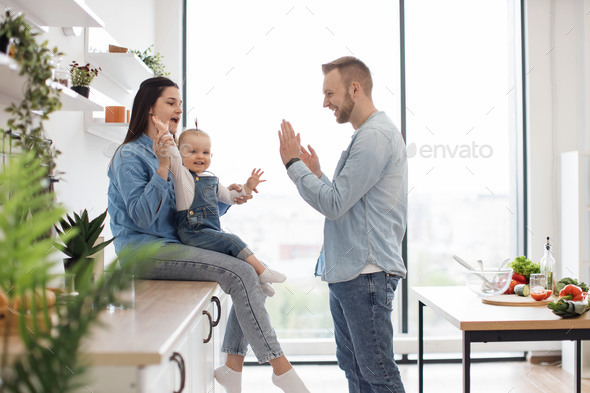 Mom and dad playing clapping game with daughter in kitchen