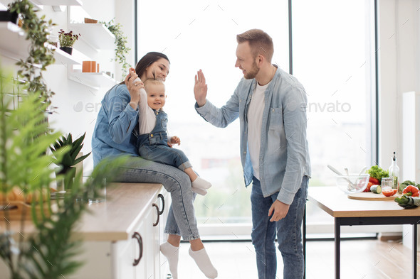 Mom and dad playing clapping game with daughter in kitchen