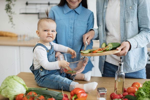 Funny child making angry face while holding bowl for salad