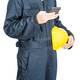 Worker standing in blue coverall holding hardhat and use smartphone - PhotoDune Item for Sale