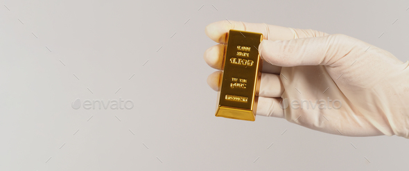Hand wear latex glove and hold gold bar on white background.