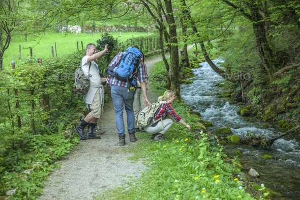 Friends with backpacks walking in nature near the river