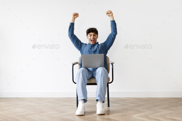Excited Arabic Man Shaking Fists Using Laptop In Amrchair Indoor