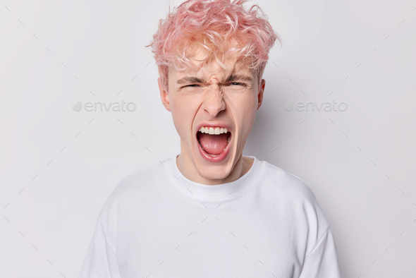 Furious enraged pink haired man with grumpy grimace on his face has mouth opened in shout ready to