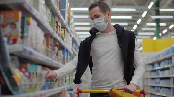 Man in Mask Shopping for Baby Care Products in the Supermarket alt