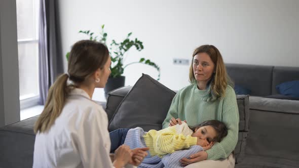 Mother with Little Daughter Talking to Health Visitor at Home alt