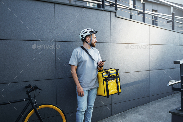 Express food delivery courier with insulated bag holding phone.