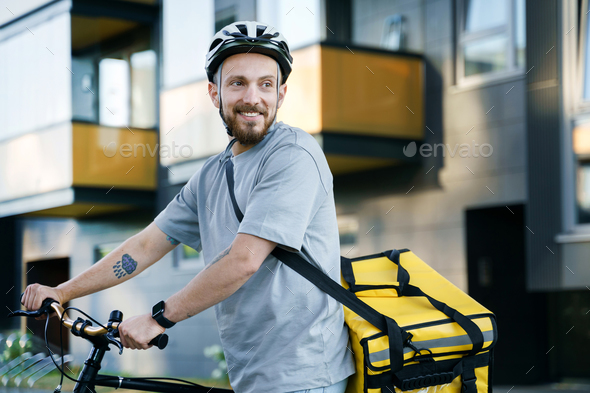 Express food delivery courier with insulated bag standing with bicycle.