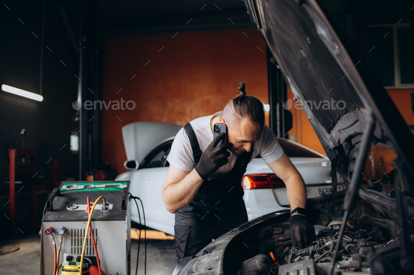 Auto mechanic talking on mobile phone in auto repair shop