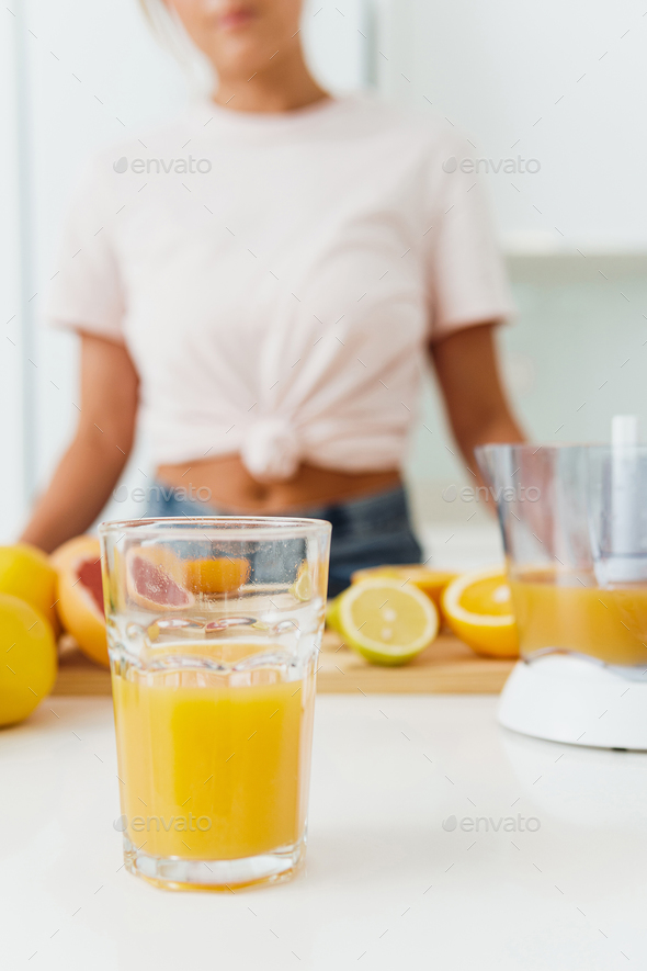 Glass of orange juice and citrus juicer on kitchen table Stock Photo by