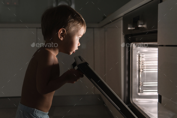 Curious baby boy opens the hot oven.