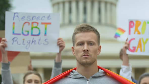 Young Man Raising Rainbow Flag, LGBT Rights Rally Participant, Pride March alt