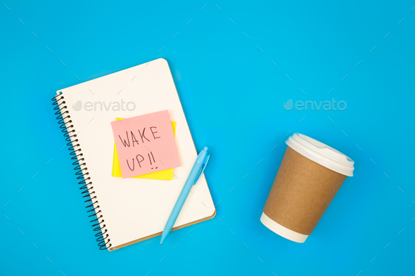 Paper cup and notebook with paper reminder with text Wake up, top view ...