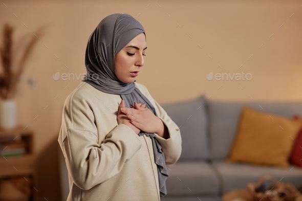 Young Islamic woman in hijab expressing gratitude to her God during pray