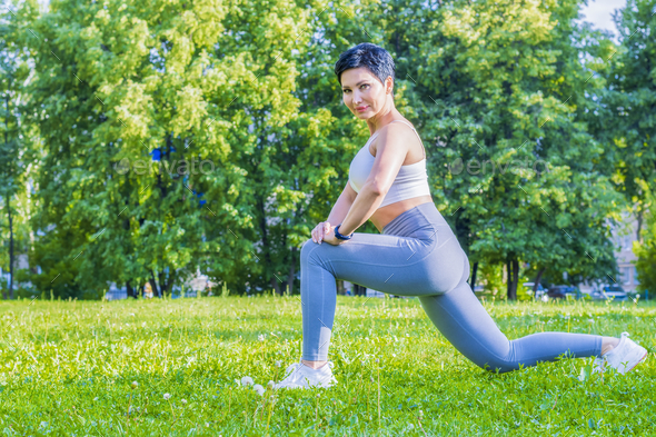 A middle-aged woman in a tracksuit performs exercises to stretch the muscles of the legs