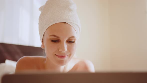 Young Beautiful Woman with Towel on a Bed in a Hotel Room Dressed in a White alt