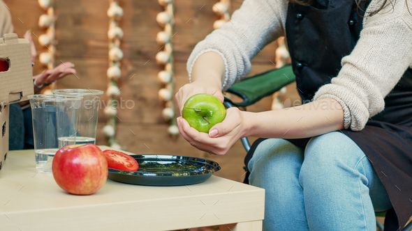 Small business owner cutting apples to give sample to cheerful clients
