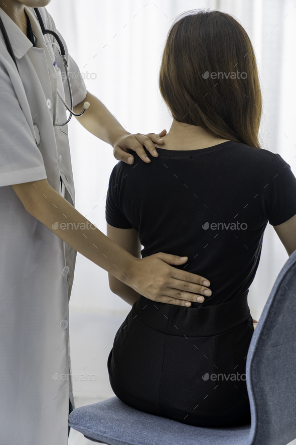 Female doctor doing physiotherapy to treat back. Female office worker back pain treatment. Doctor, c