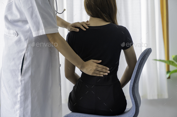 Female doctor doing physiotherapy to treat back. Female office worker back pain treatment. Doctor, c