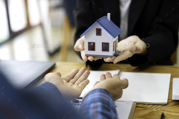 real estate agent salesman holds a model of a house and sends it to customers as an example, a sampl