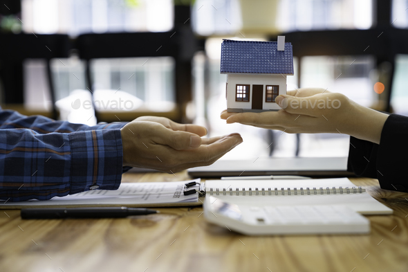 real estate agent salesman holds a model of a house and sends it to customers as an example, a sampl