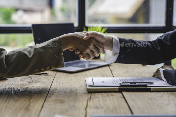 Business people shaking hand after business signing contract and resume on desk in meeting room at c
