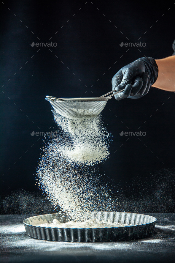 front view female cook pouring white flour into the pan on dark