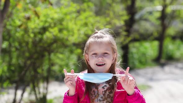 Portrait of little girl with medical face mask standing outdoor