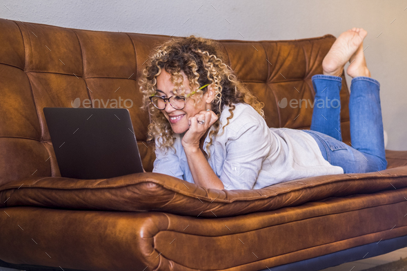 Portrait of young adult woman enjoying indoor relax leisure activity surfing the web on a laptop