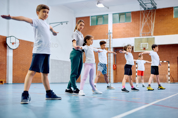 Sports teacher assisting her students during physical activity class at ...