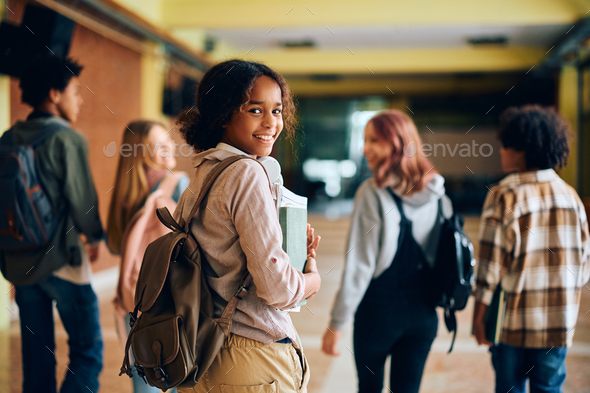 Happy black teenage girl in high school hallway looking at camera. Stock  Photo by drazenphoto