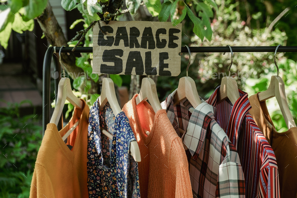 Garage sale, clothes for sale hanging on hanger outdoors. Stock