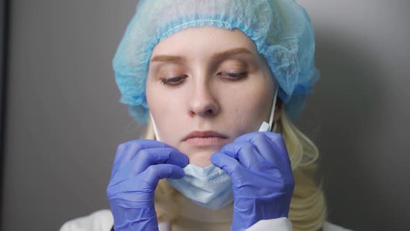 Sad Tired Female Doctor Nurse in Protective Suit or Costume Taking Off Mask and Glasses After Long alt