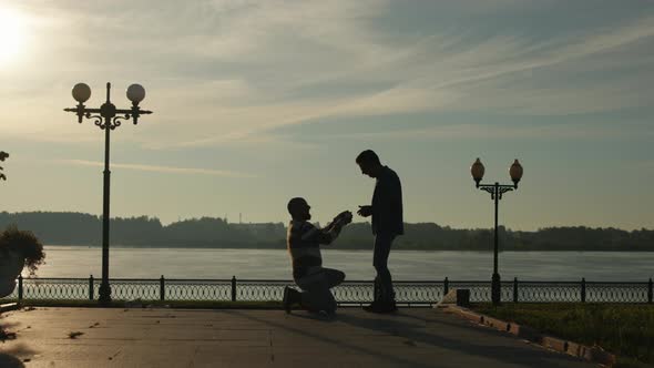 Gay Marriage Proposal Concept. Silhouette of Two Men. Guy Gifts a Wedding Ring To His Fiance alt