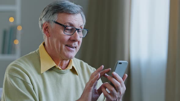 Excited Middle Aged Retired Man with Glasses Holding Telephone Make Online Shopping Communicates alt