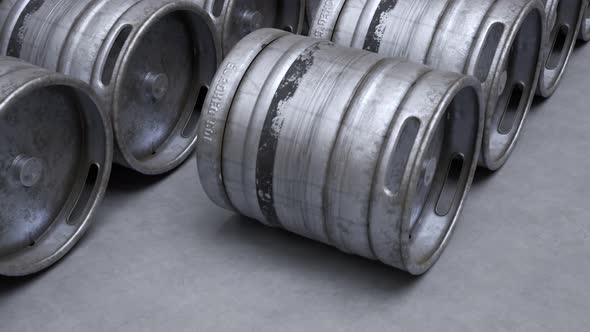 Multiple metal beer kegs being rolled on the ground in endless, seamless loop.