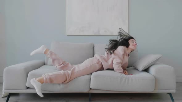 Exhausted female student getting sleep on sofa to rest in living room with modern interior, daytime.