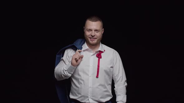 A Sexy Man in a White Shirt with an Unbuttoned Red Tie and a Jacket on His Shoulder Laughs Sincerely alt